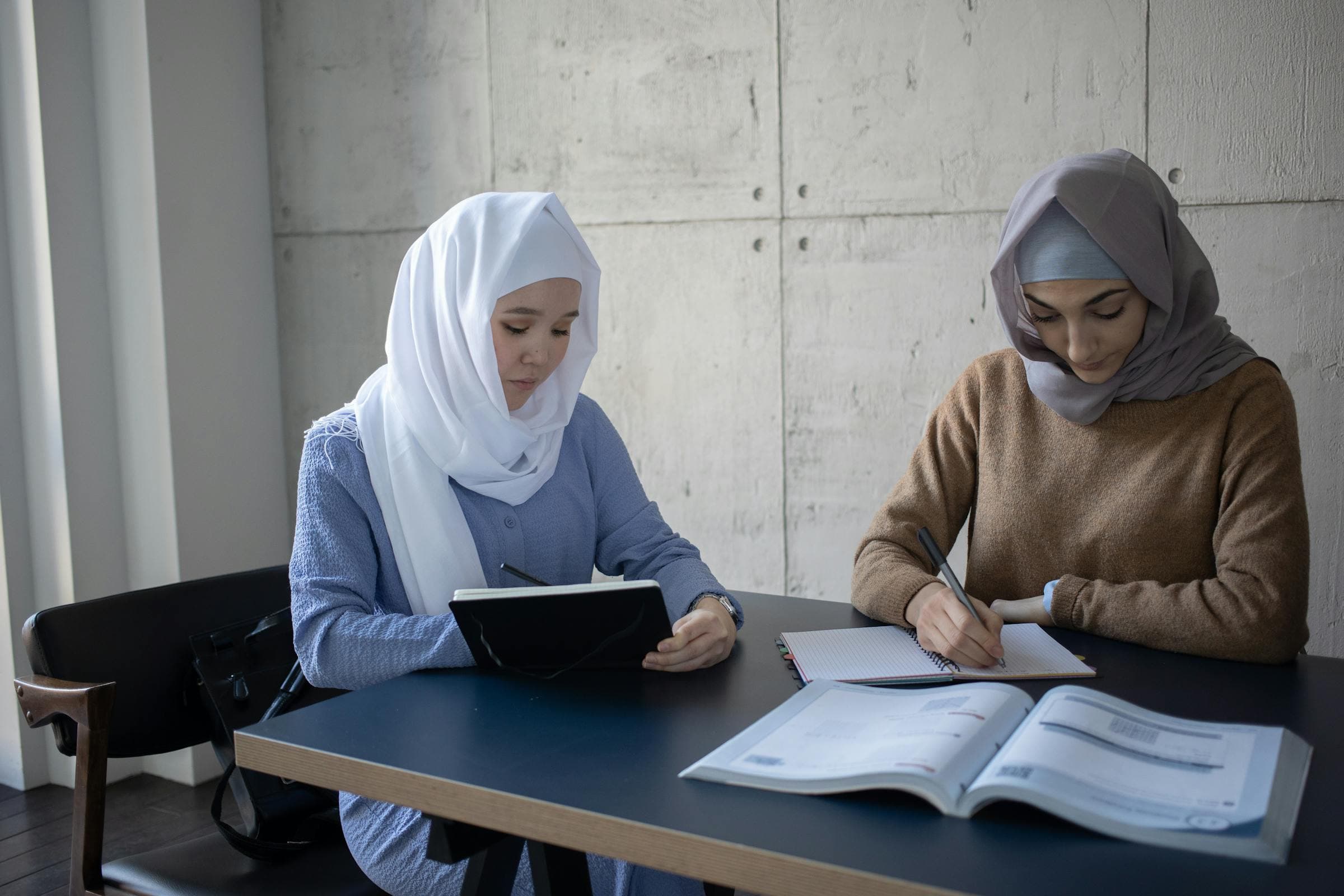 A senior student tutoring a junior over open textbooks